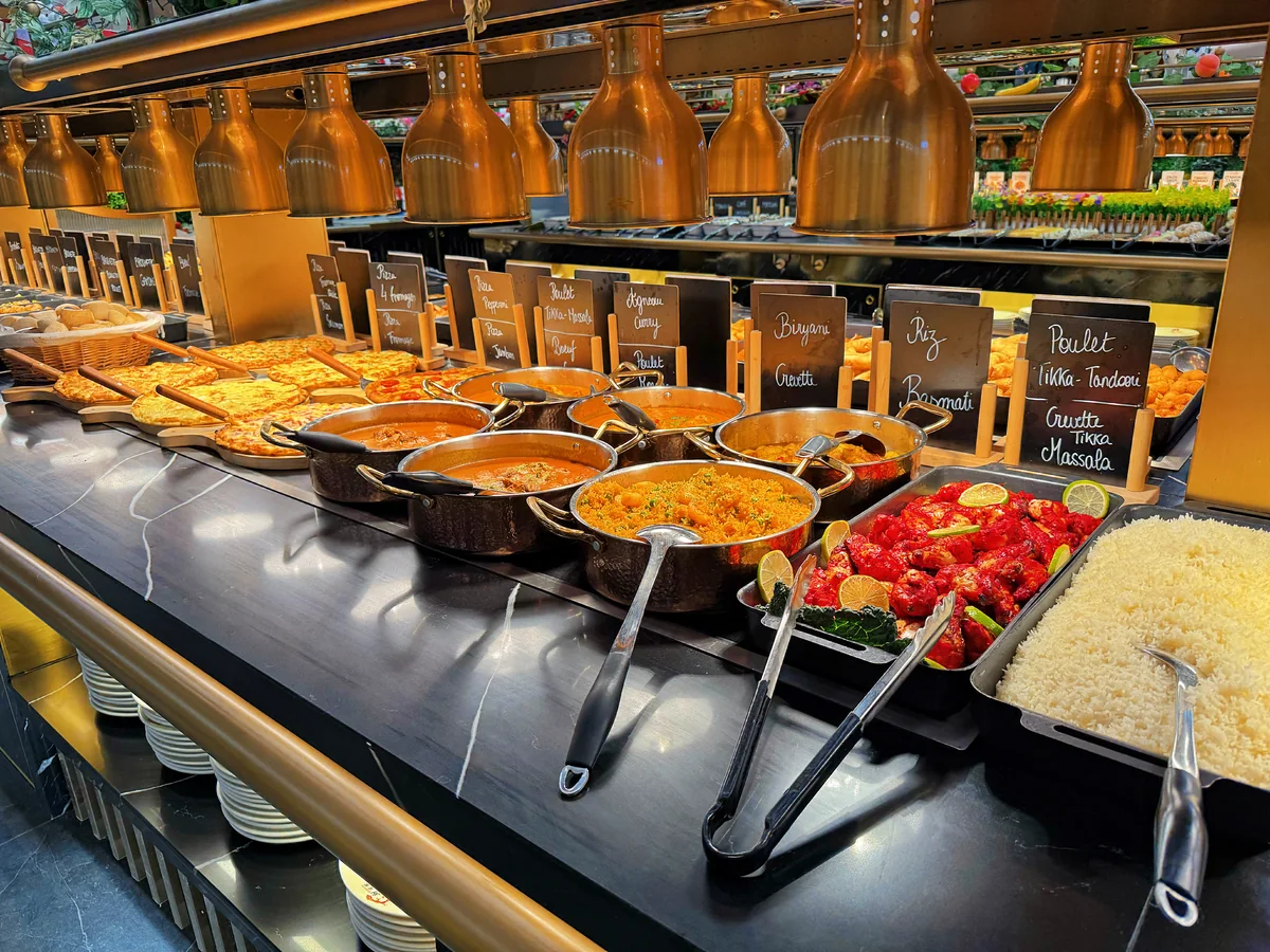 La grande allée des plats chauds du buffet sous les lampes dorées